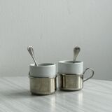 2 porcelain cups with metal supports and small spoons.