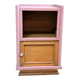 Pink bedside table with haberdashery and raw wood.