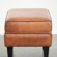 Handy sheepskin ottoman with warm colours finished with black piping