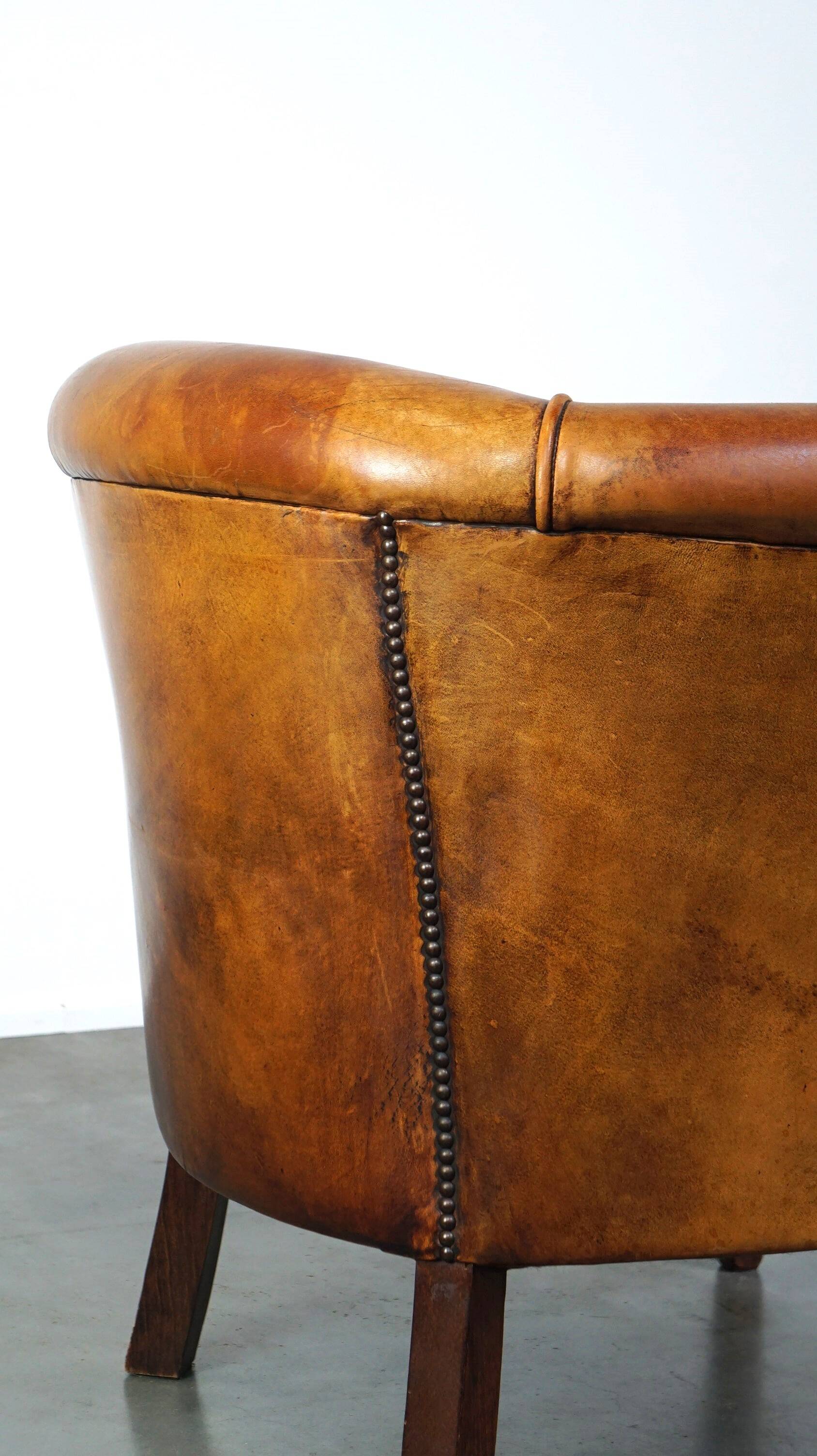 Neat and subtle sheepskin club chair, finished with decorative studs and a fixed seat cushion