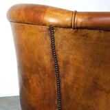 Neat and subtle sheepskin club chair, finished with decorative studs and a fixed seat cushion