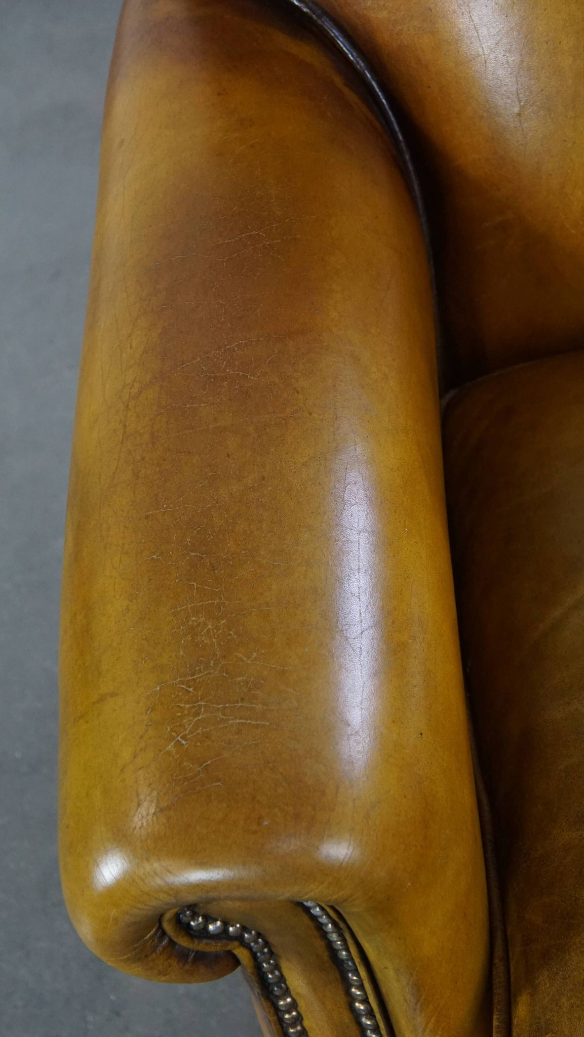 Comfortable large yellow English-style leather armchair with a fine finish and decorative nails