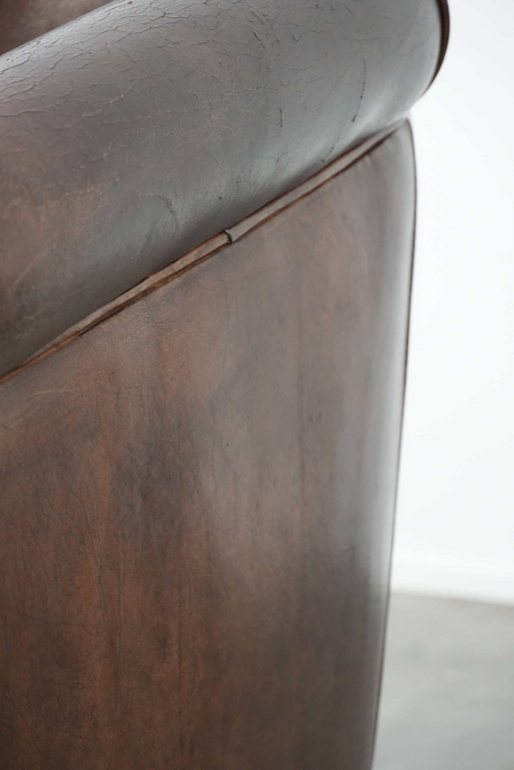 Dark brown vintage club armchair in English style made of sheepskin leather