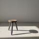 Small brutalistic tripod stool in dark wood tapered feet circular seat