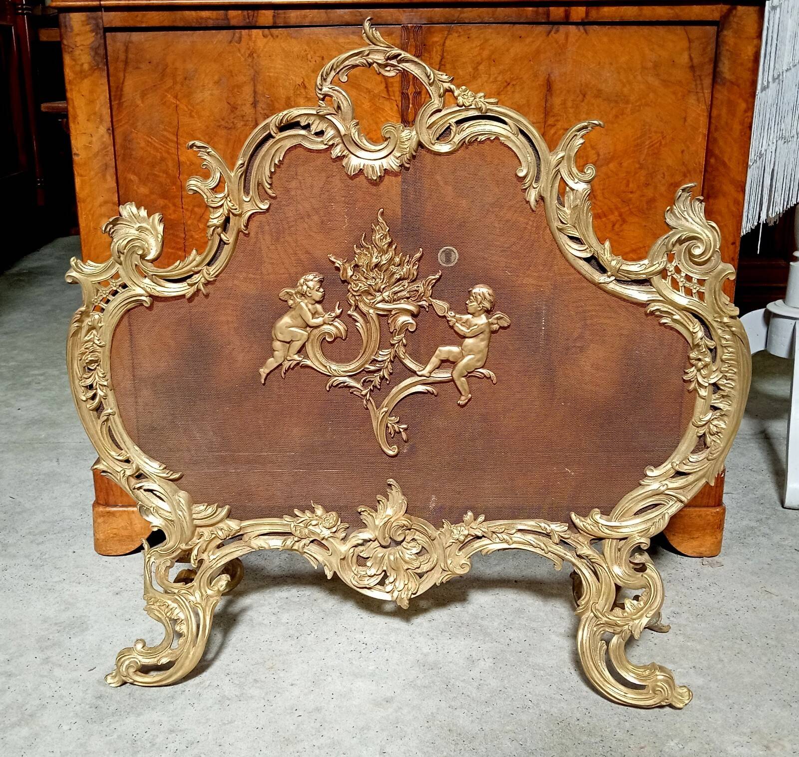 Large gilded bronze fireplace screen decorated with putti and rocaille motifs.