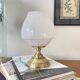Antique white opaline glass globe table lamp with a brass base.