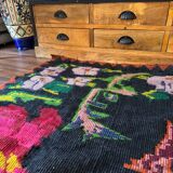 Bohemian floral design, handwoven wool rug, black background with colorful flowers
