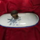 Old wall fountain in enamelled sheet metal decorated with blue flowers on a white background
