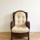 Vintage armchair in rattan and wicker with beige cushion.