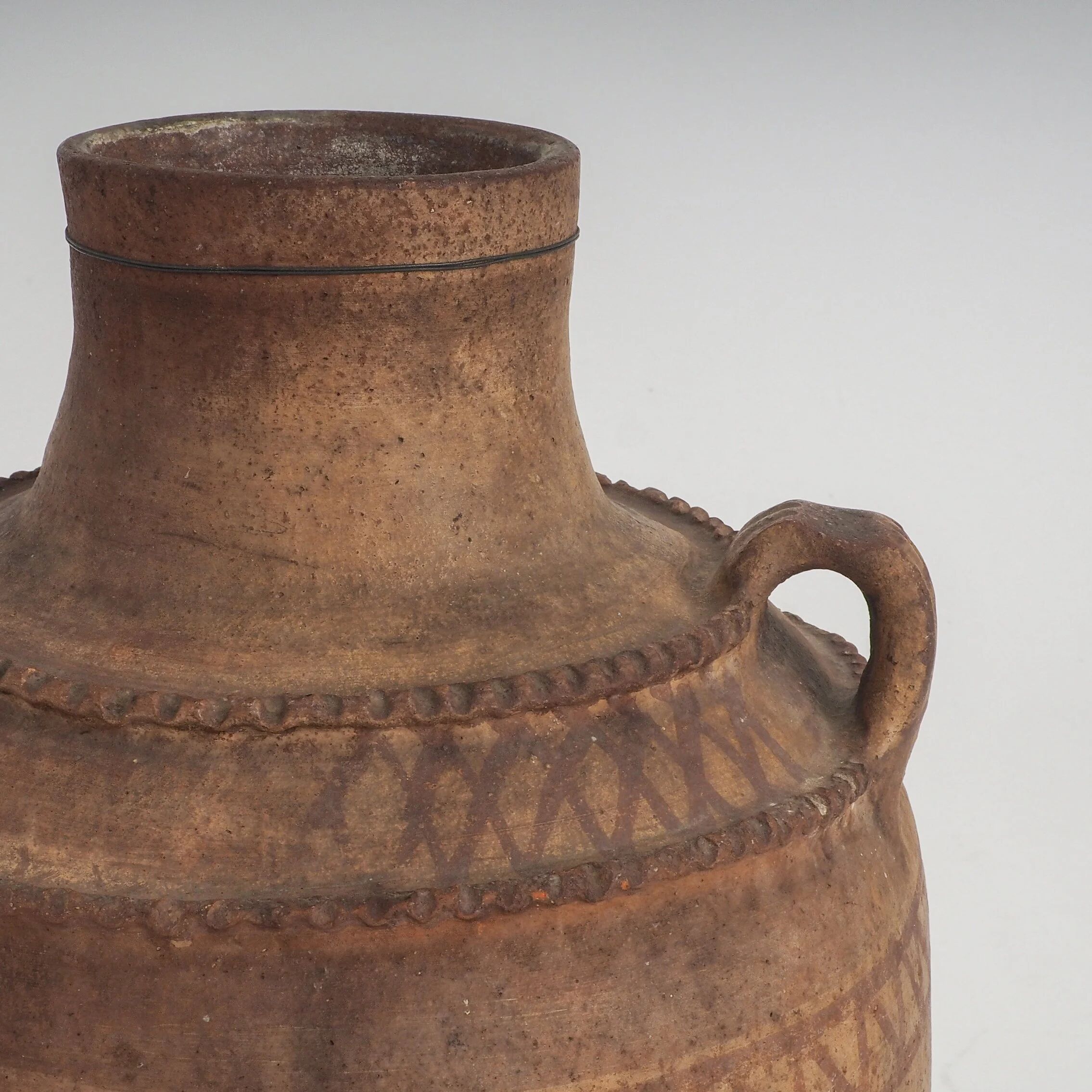 Vaisseau en terre cuite primitive avec des détails géométriques peints à la main.