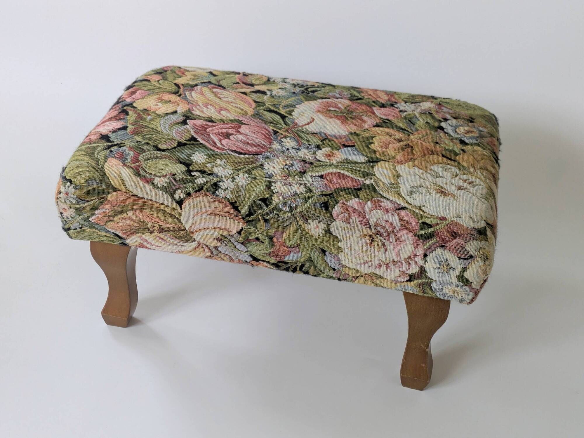 Large vintage upholstered footstool with curved legs.