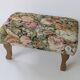 Large vintage upholstered footstool with curved legs.