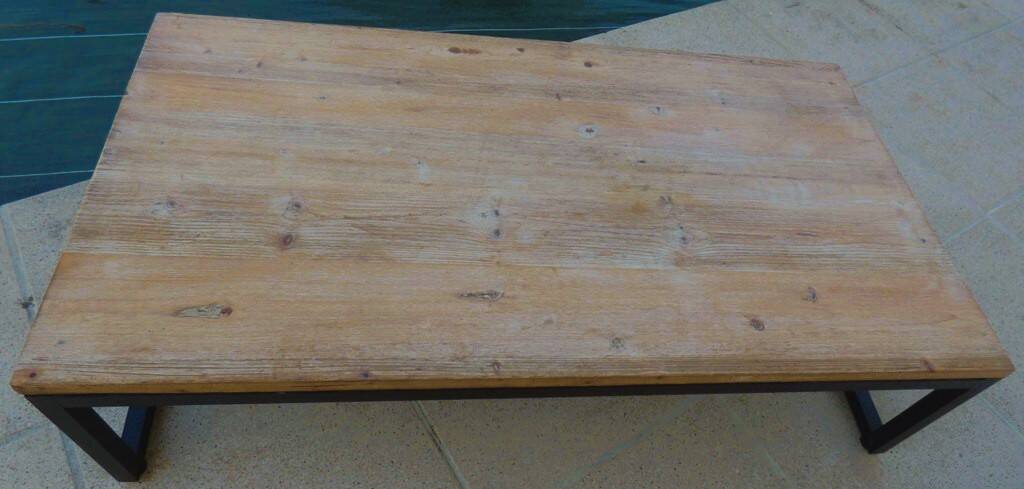 Industrial style coffee table with wooden top supported by a metal base -