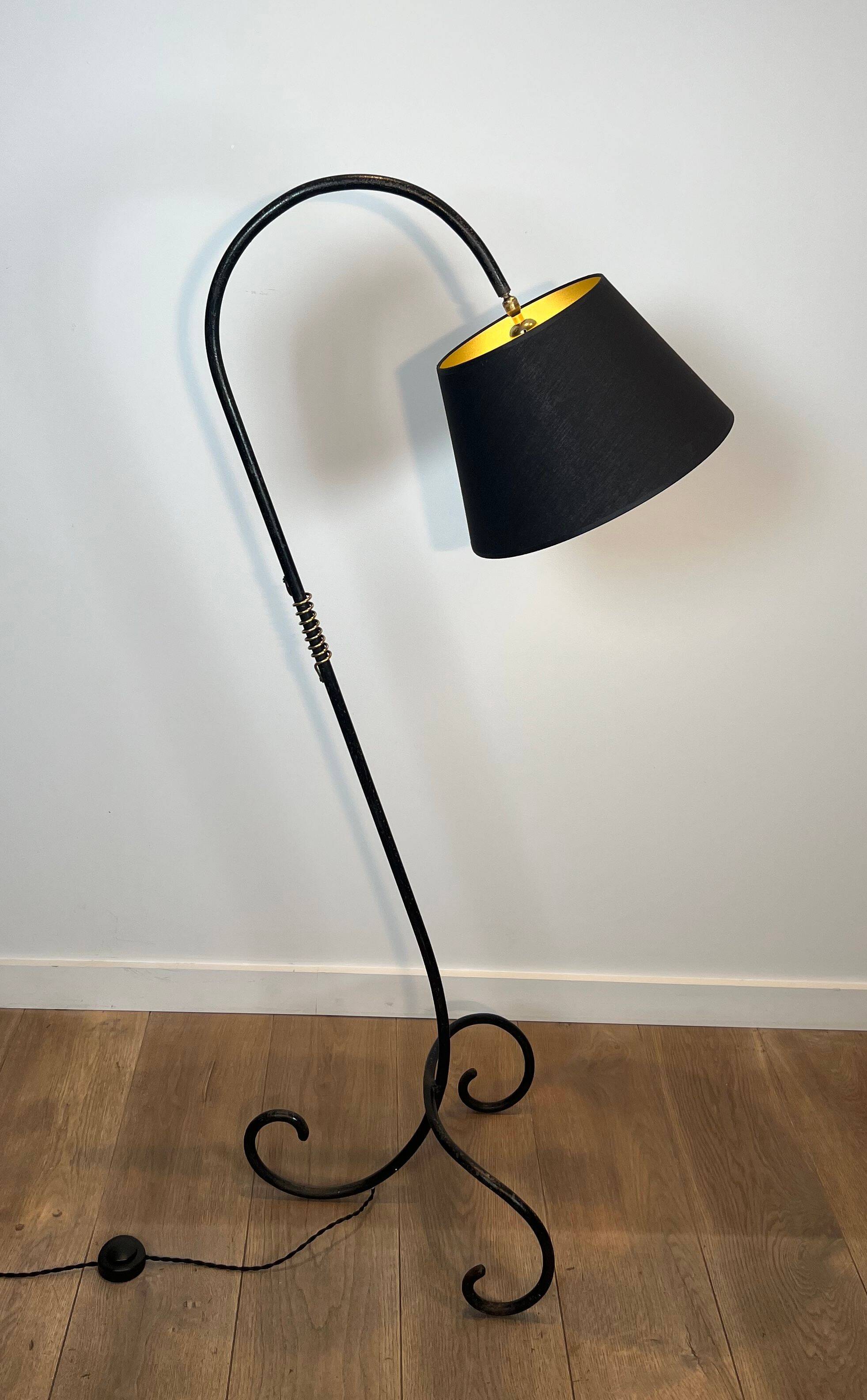 Design floor lamp in black lacquered metal and brass.