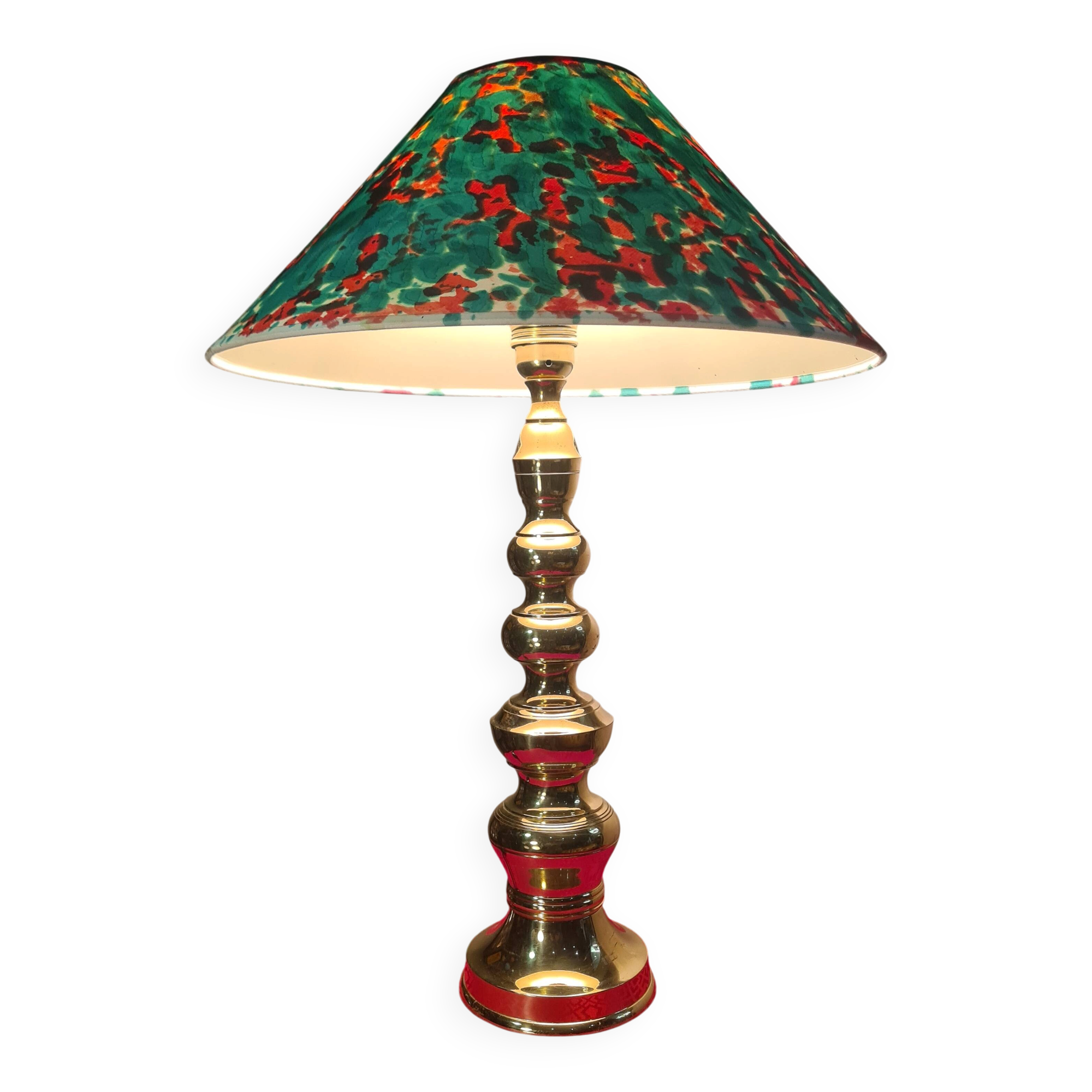 This elegant table lamp features a sculptural base in shiny gold brass.