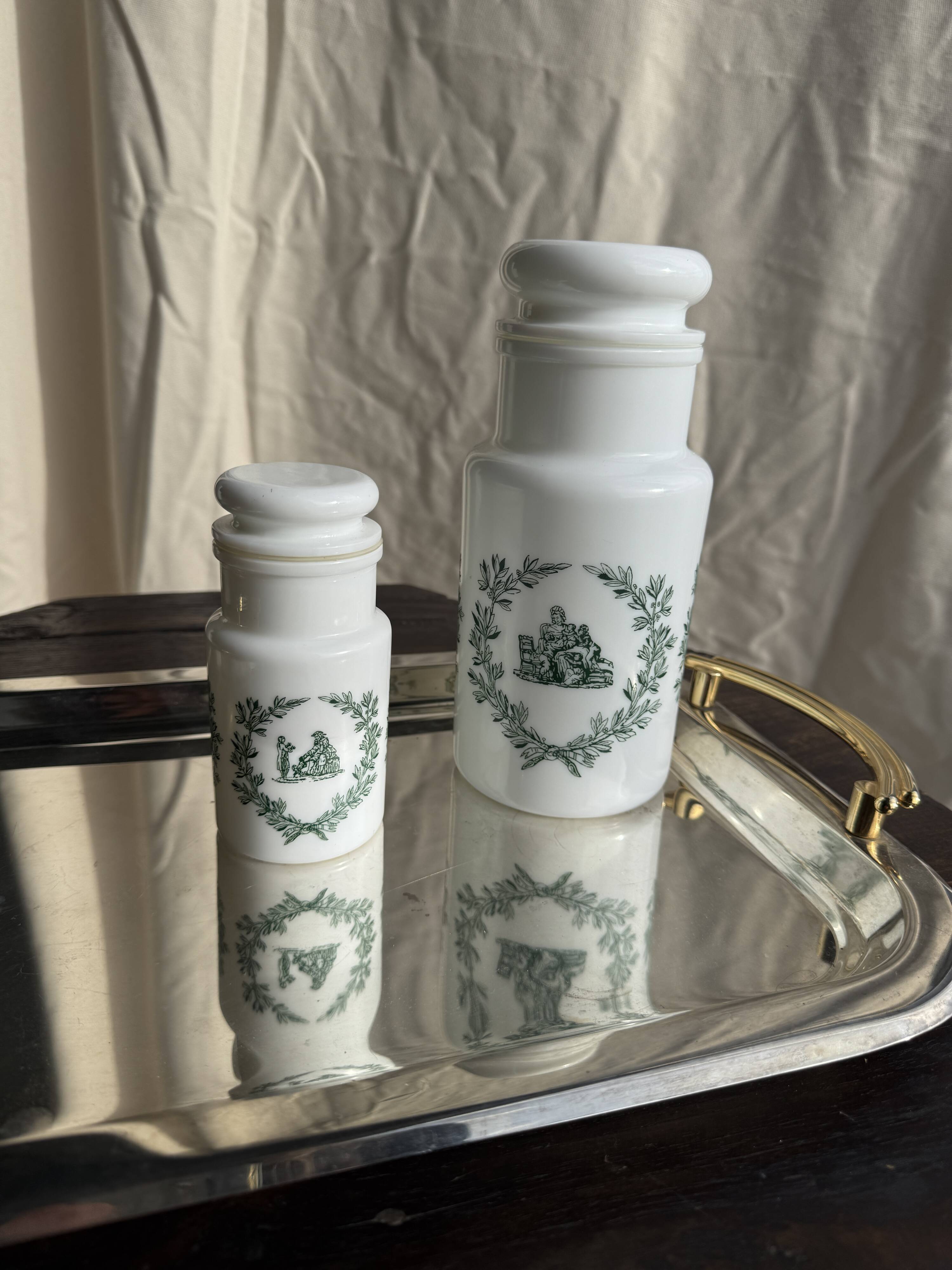 A pair of white glass bottles with Italian green patterns.