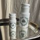 A pair of white glass bottles with Italian green patterns.