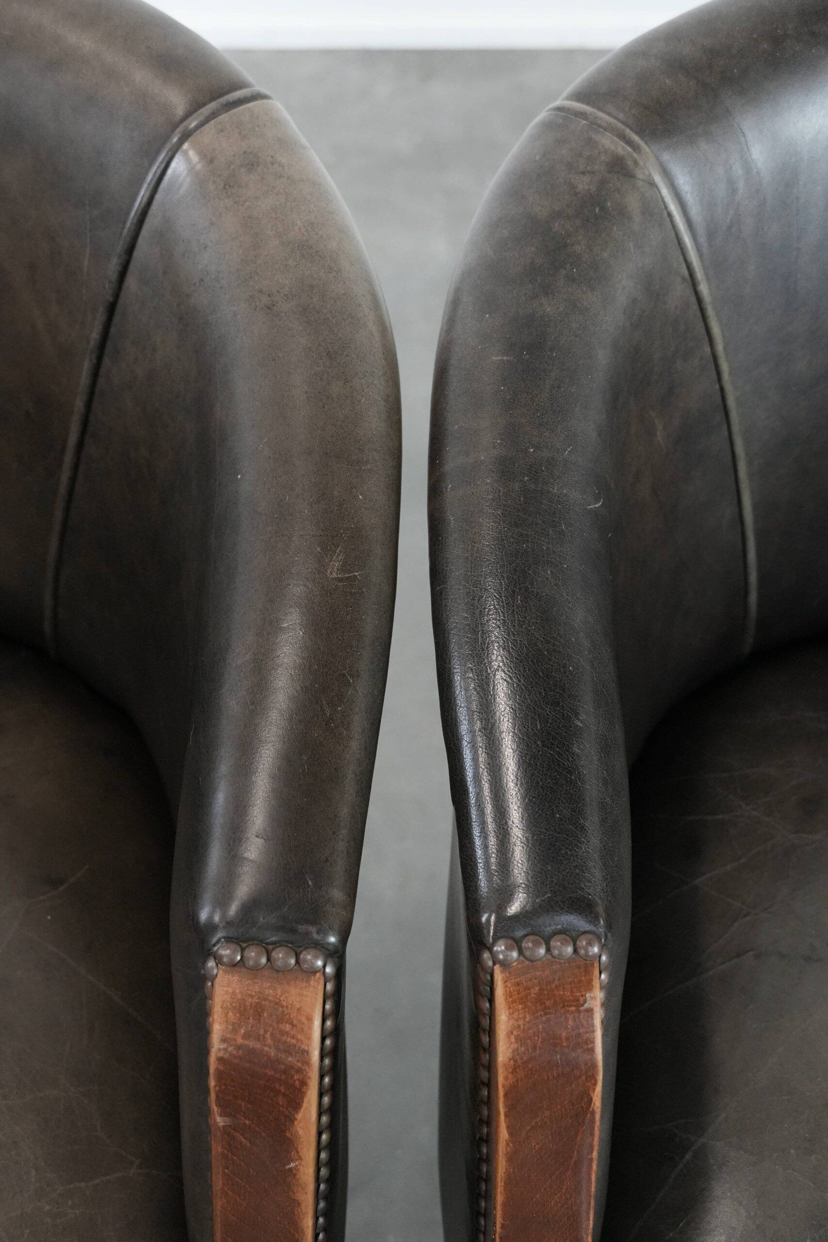 Set of two cowhide and wooden tub chairs with a sturdy colour scheme