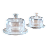 2 transparent glass butter dishes accompanied by their matching cloches.