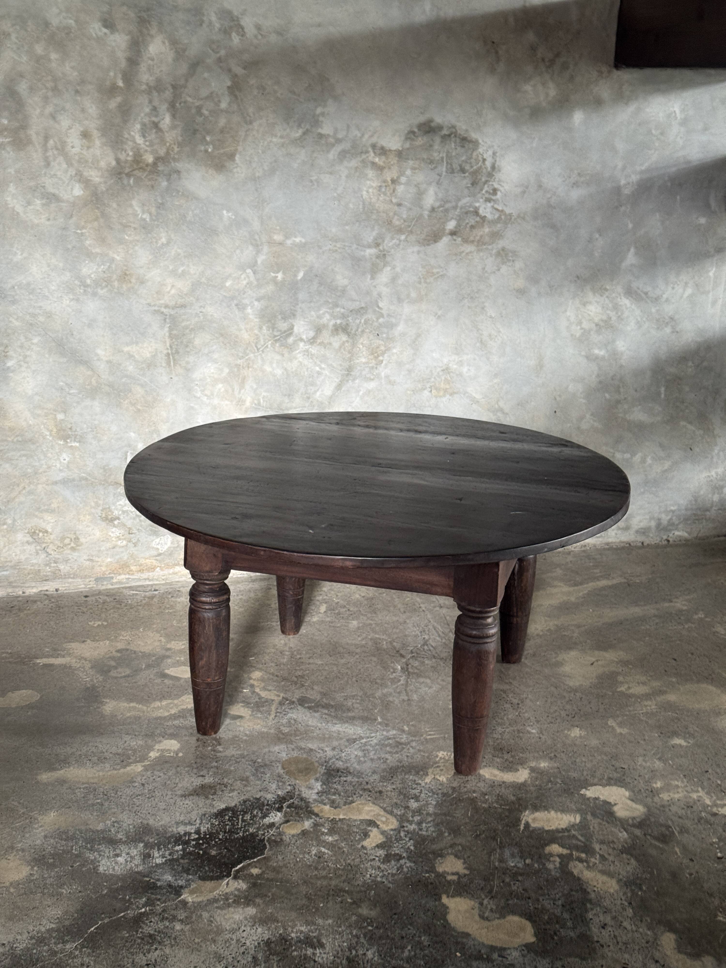 Antique round coffee table in Indonesian teak with turned legs.