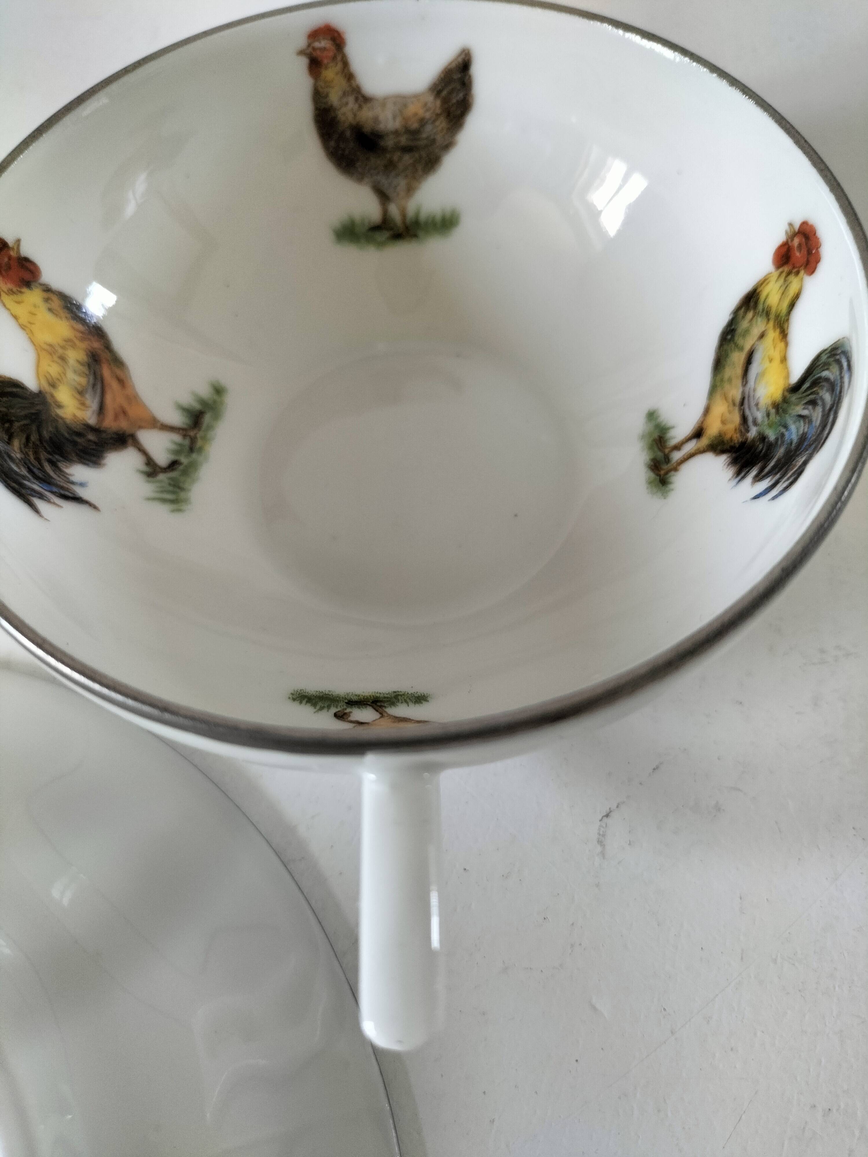 Cup and saucer in porcelain decorated with roosters and hens.