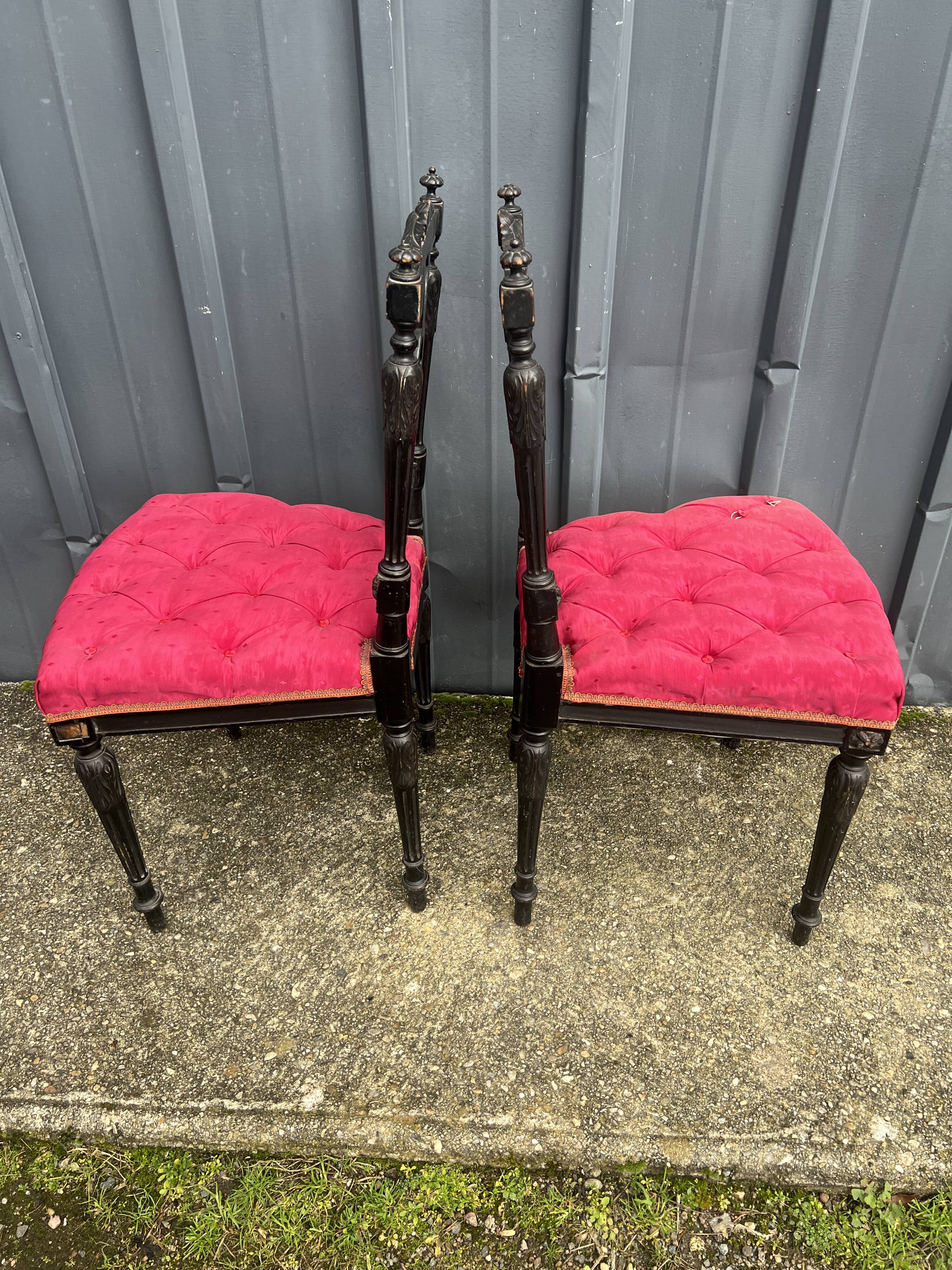Pair of black lacquered chairs with purple tufted upholstery.