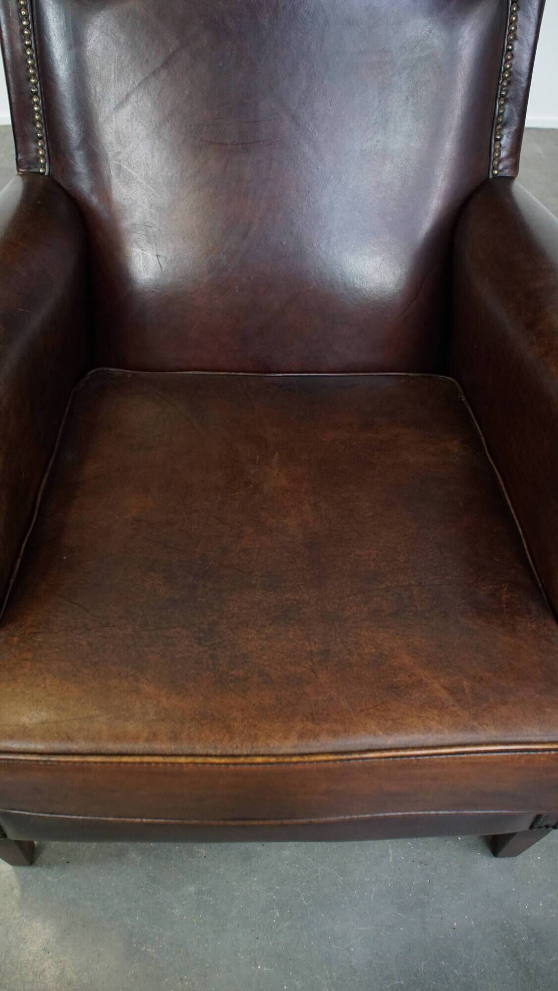 Dark brown sheepskin armchair finished with decorative nails
