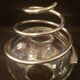 Round glass candle holder with silver-plated metal spiral.