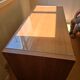 Large wooden desk with a glass top and a wheeled drawer unit.