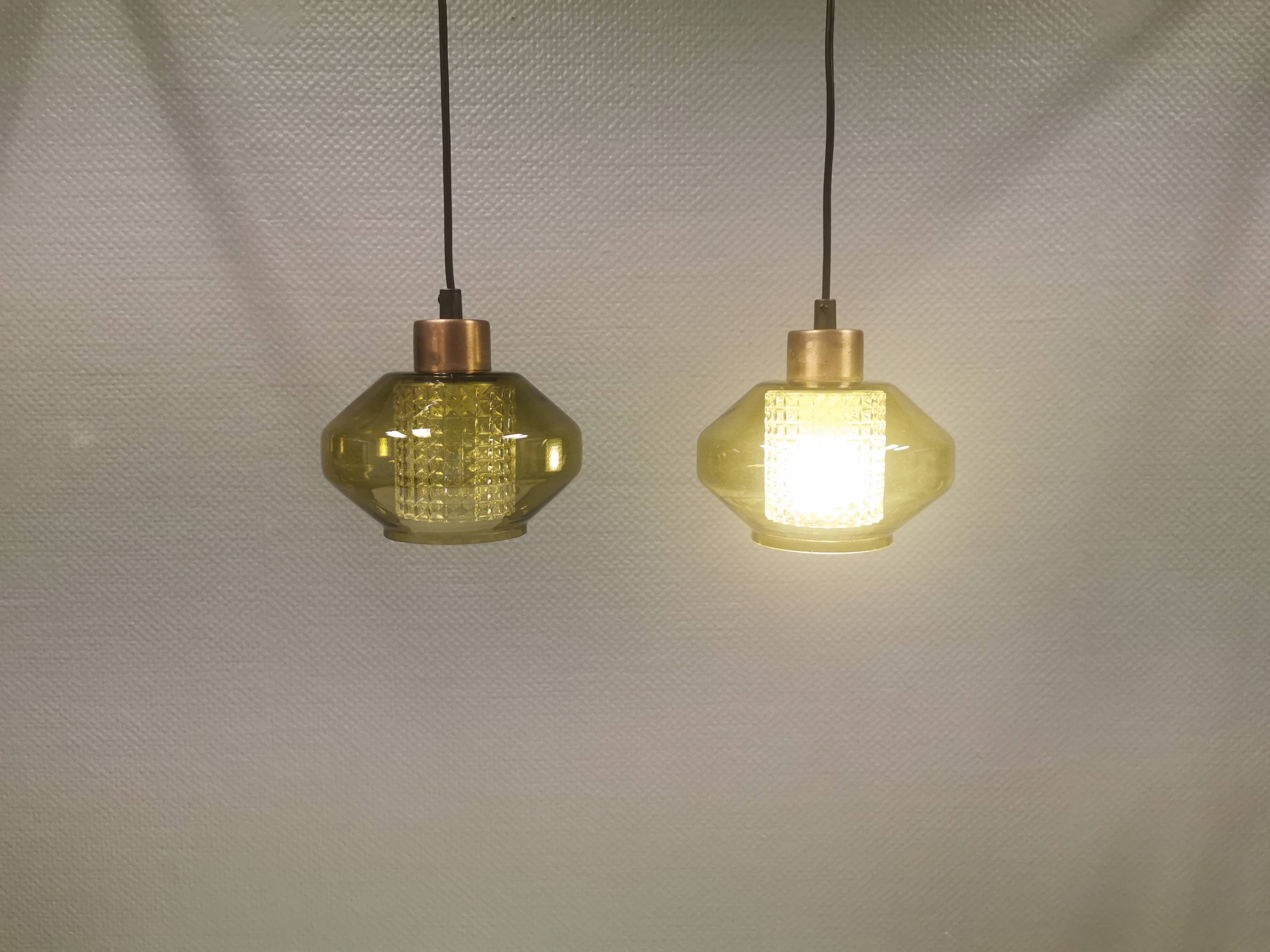 Hanging lamp with an outer shade of olive green glass and an inner shade of clear, crystal glass.