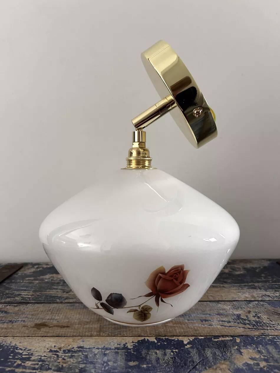 Golden tilting wall light with flowered globe