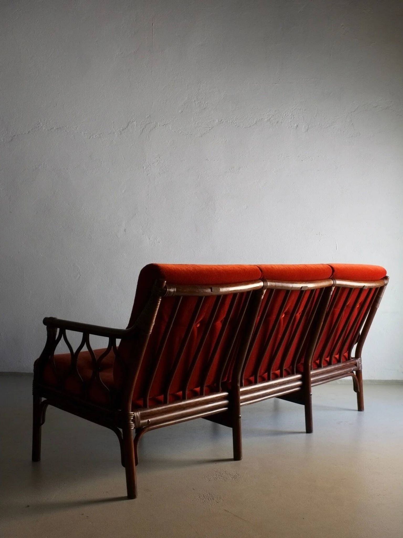 Dark rattan 3-seater sofa with red velour cushions | 1980s