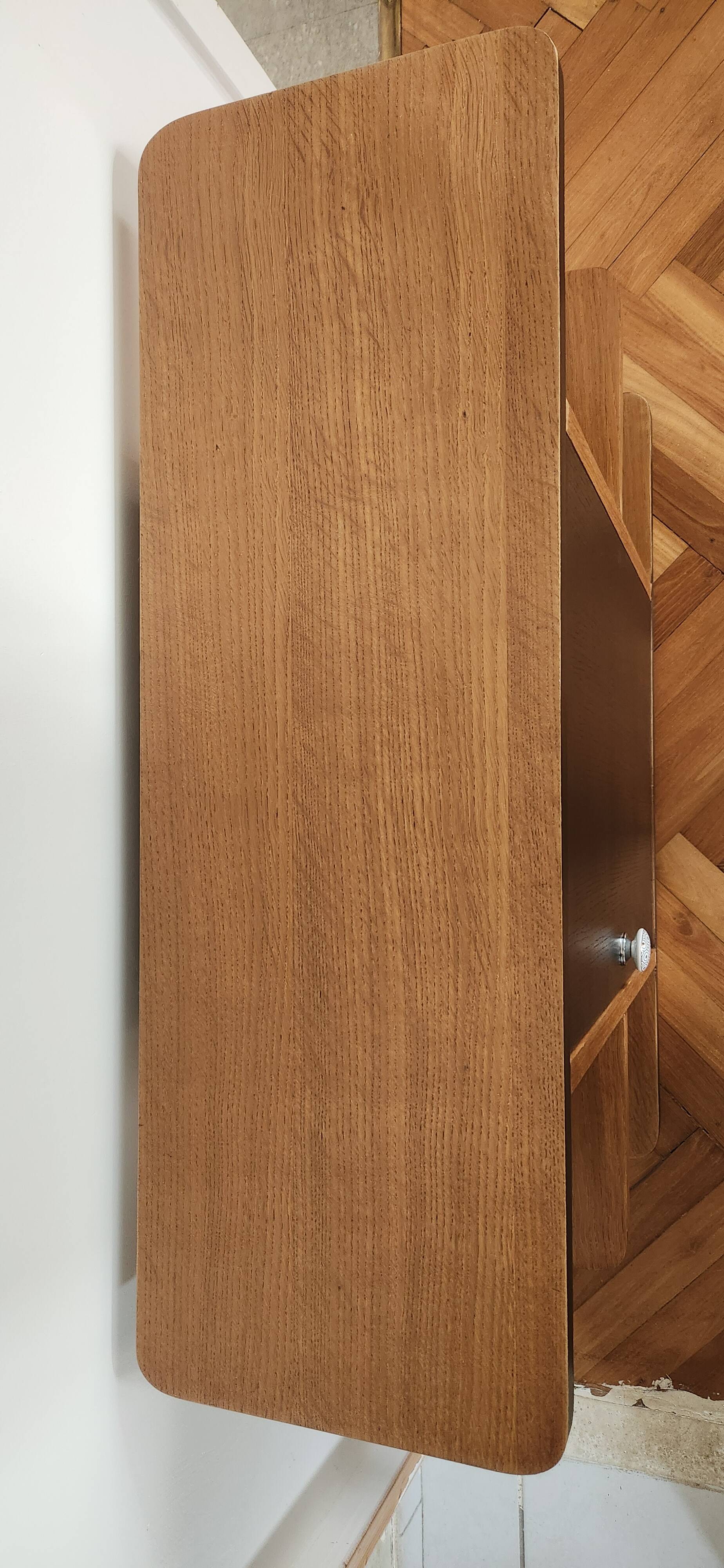 Compact bar cabinet with a pivoting door in black wood.