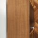 Compact bar cabinet with a pivoting door in black wood.