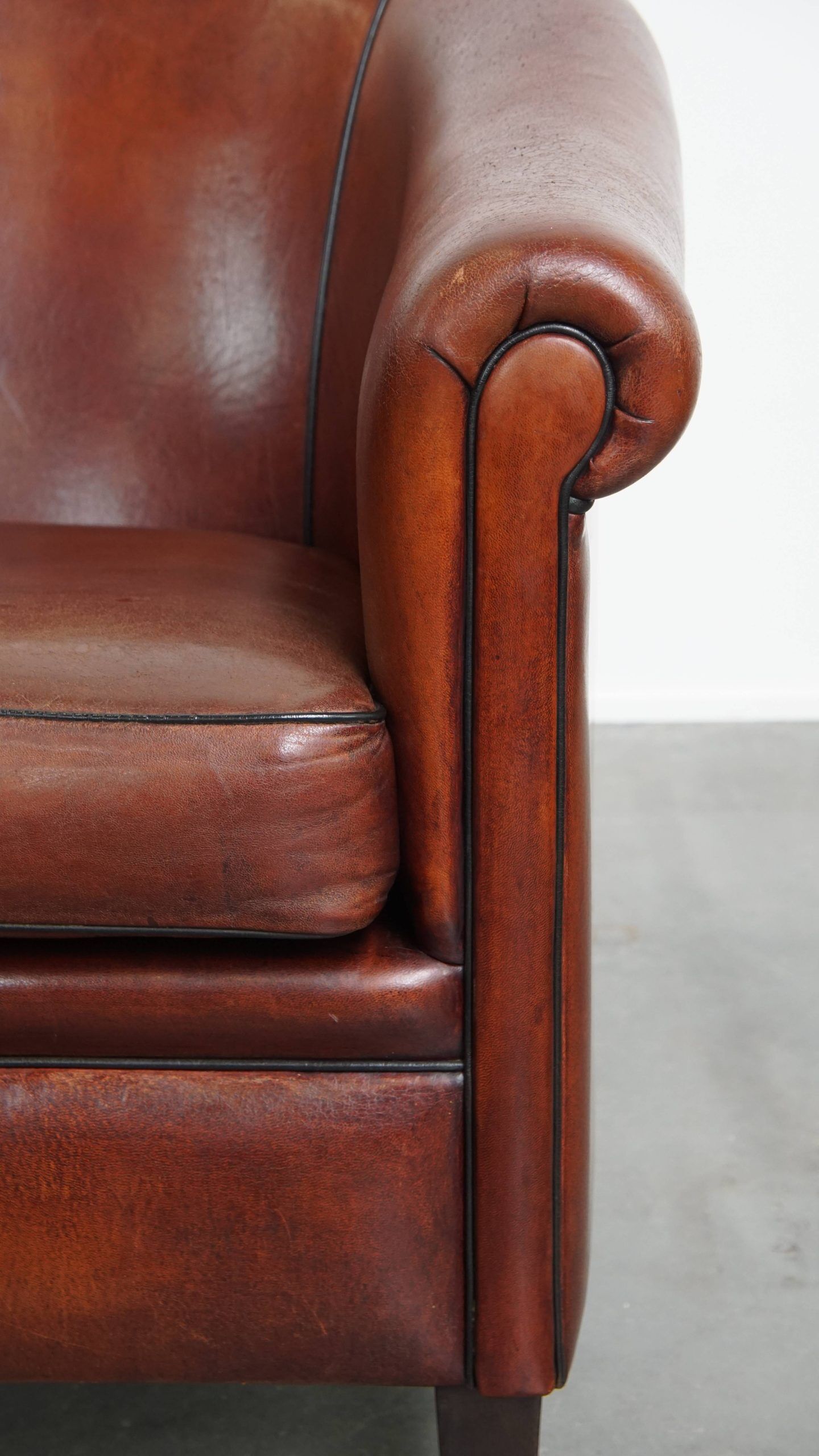 Sheepskin club armchair in a warm deep colour finished with black piping