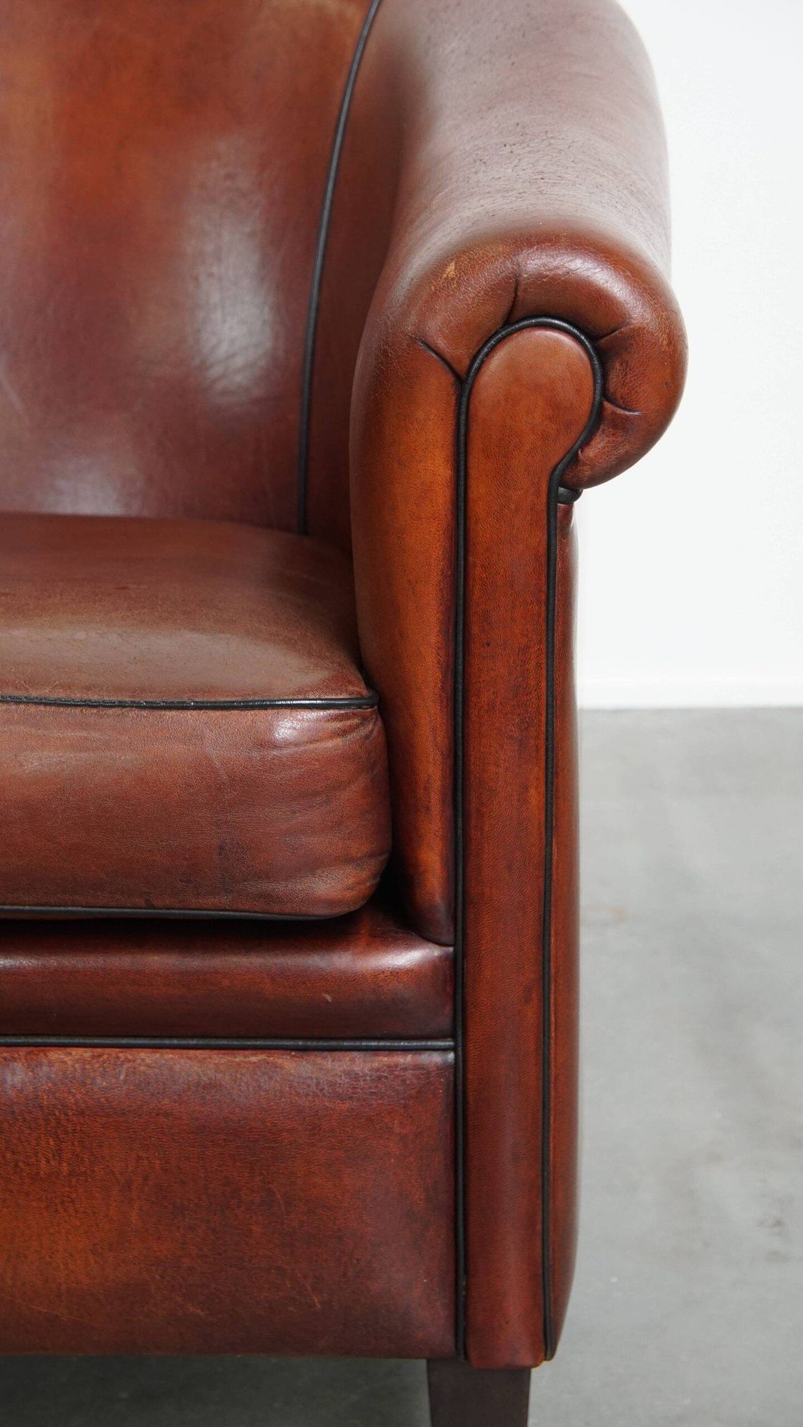 Sheepskin club armchair in a warm deep colour finished with black piping