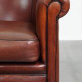 Sheepskin club armchair in a warm deep colour finished with black piping