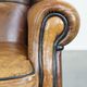 Cognac-colored sheep leather wingback chair finished with black piping