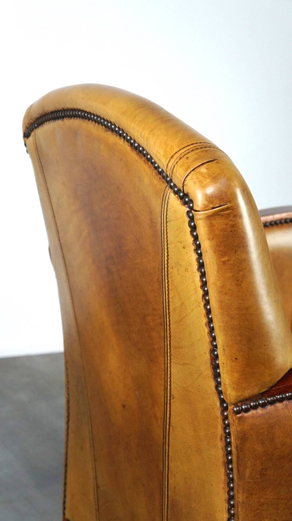 Luxurious cowhide Art Deco design armchair with wooden armrests and cognac-colored leather