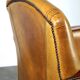 Luxurious cowhide Art Deco design armchair with wooden armrests and cognac-colored leather