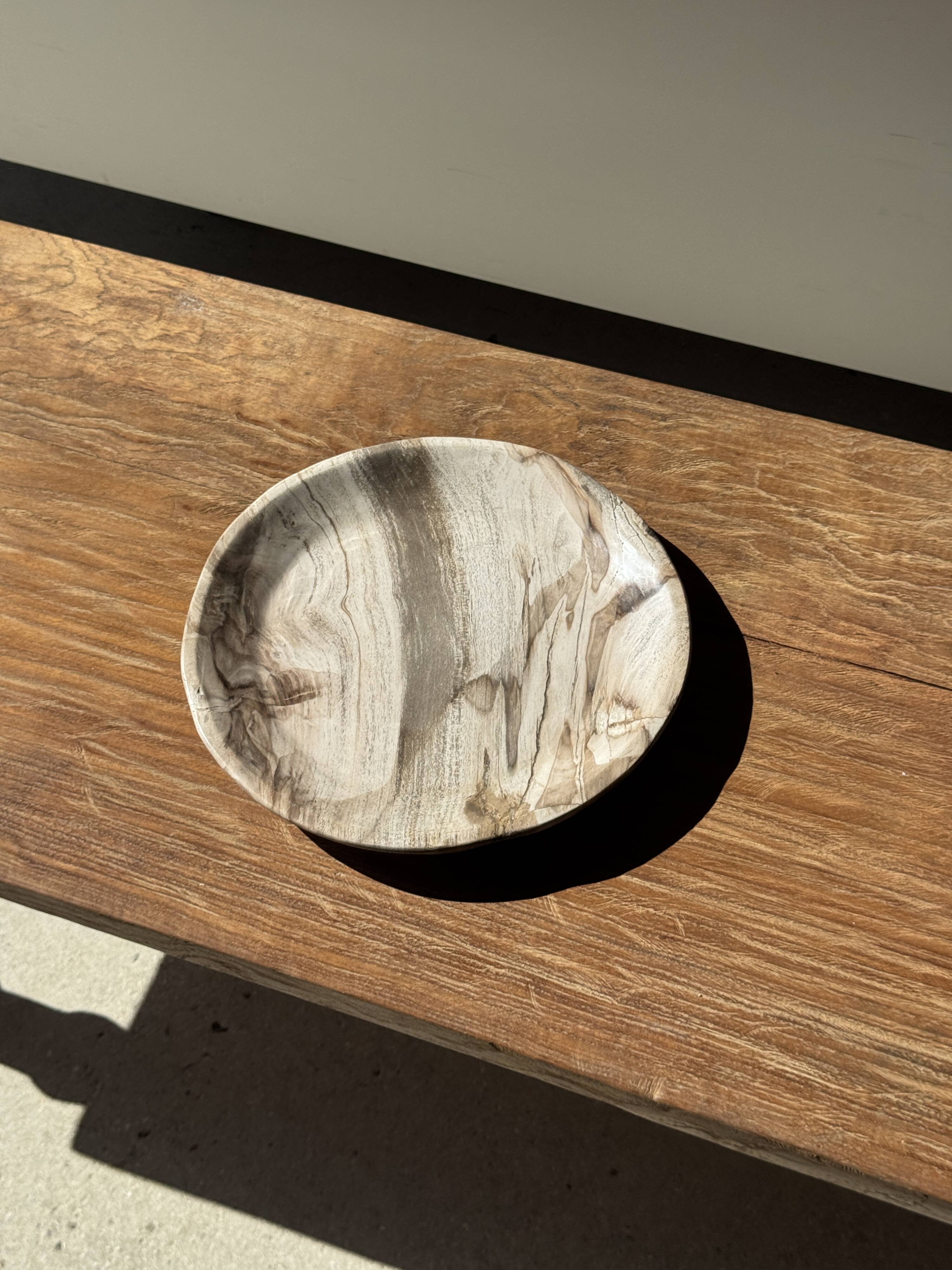 Tray, circular dish or plate made of white striped grey petrified wood.