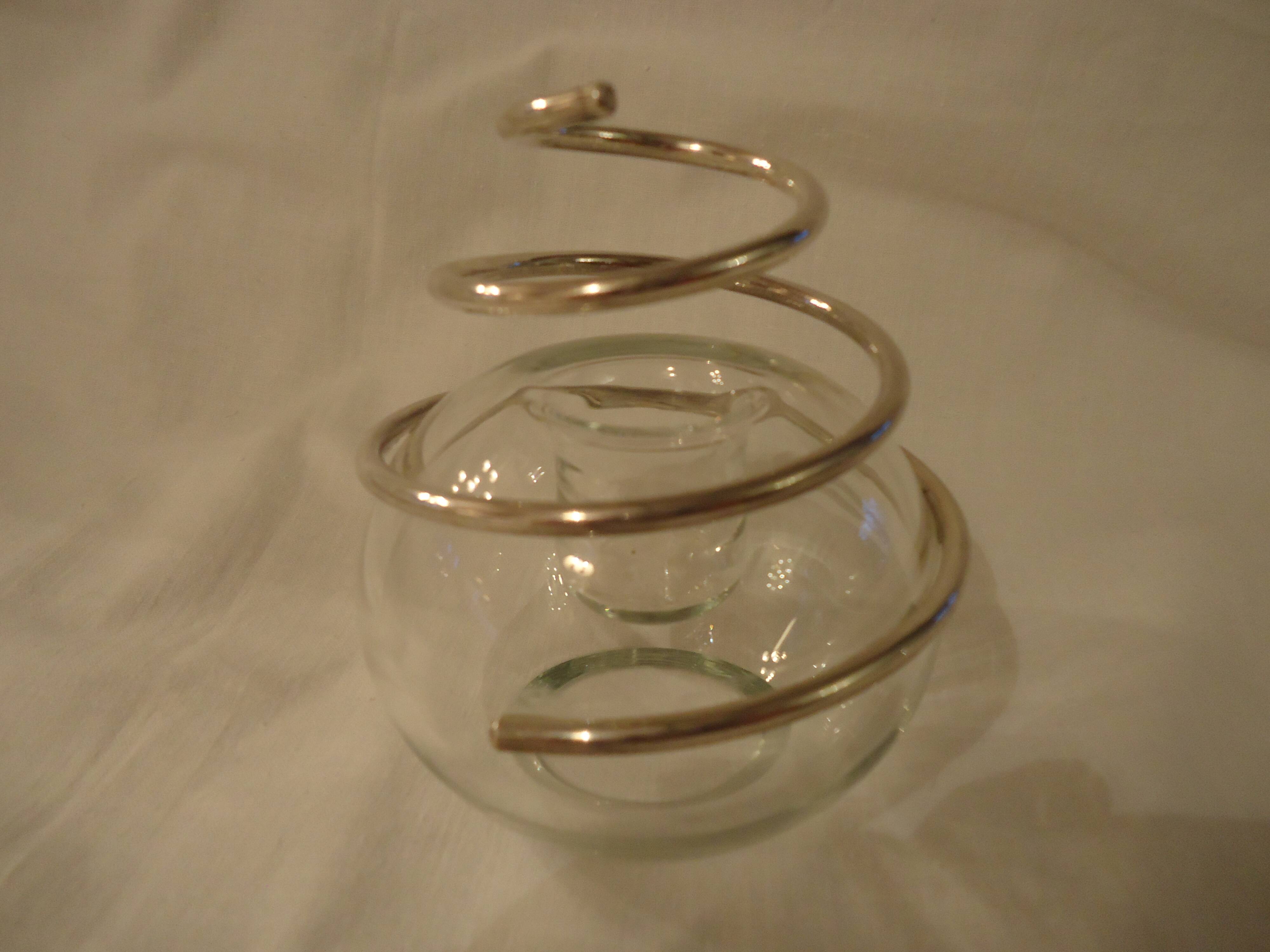 Round glass candle holder with silver-plated metal spiral.