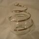 Round glass candle holder with silver-plated metal spiral.