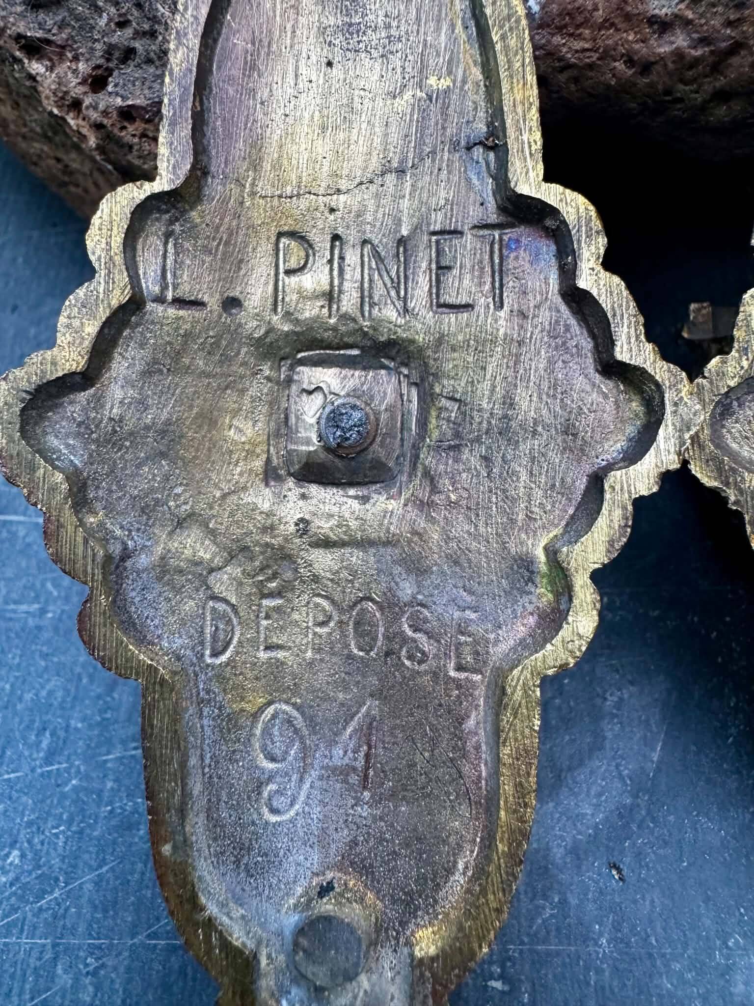 Pair of bronze wall sconces with mask, signed L. Pinet, Art Nouveau period.