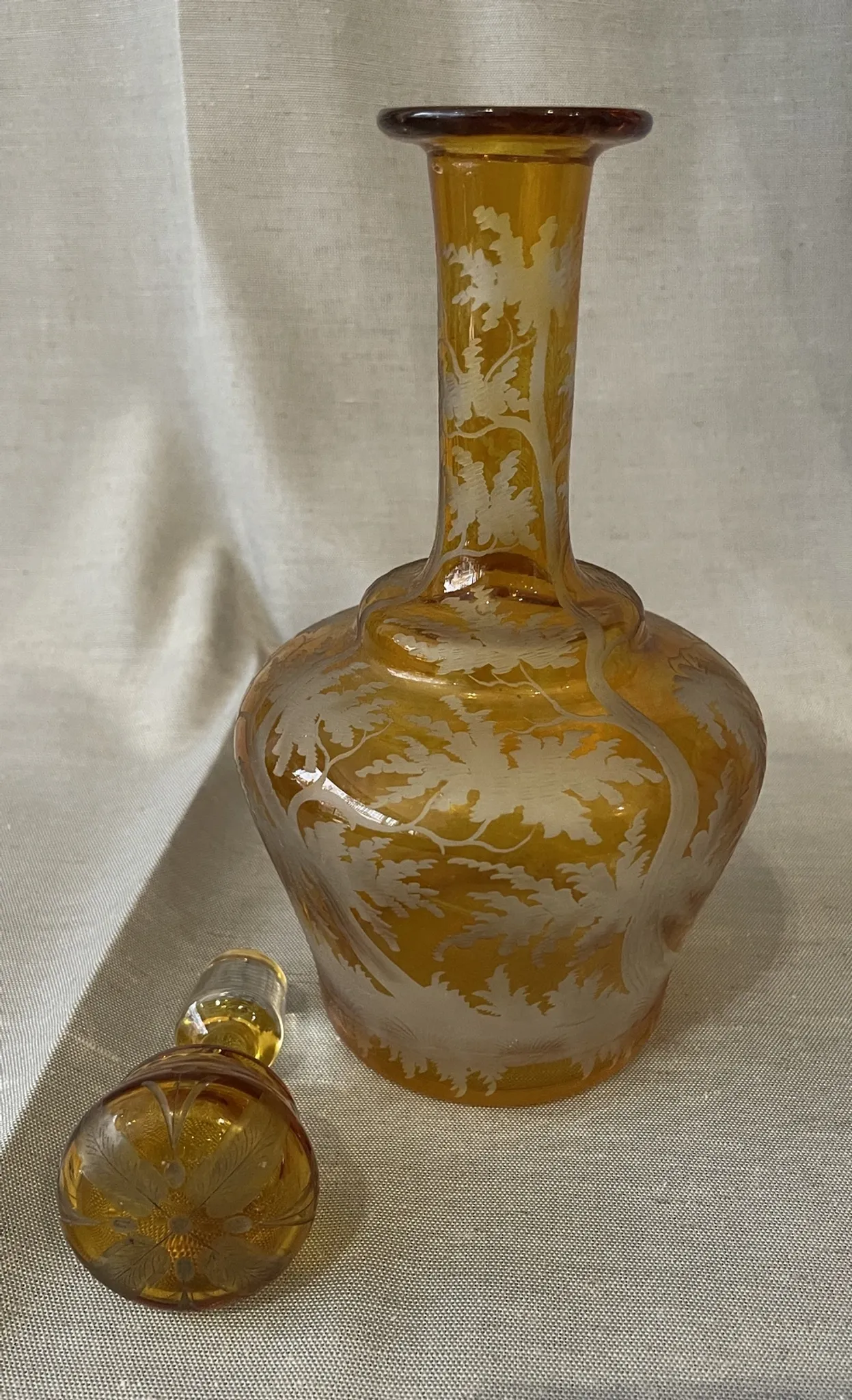 Amber bohemian glass liqueur carafe decorated with a stag in the forest.