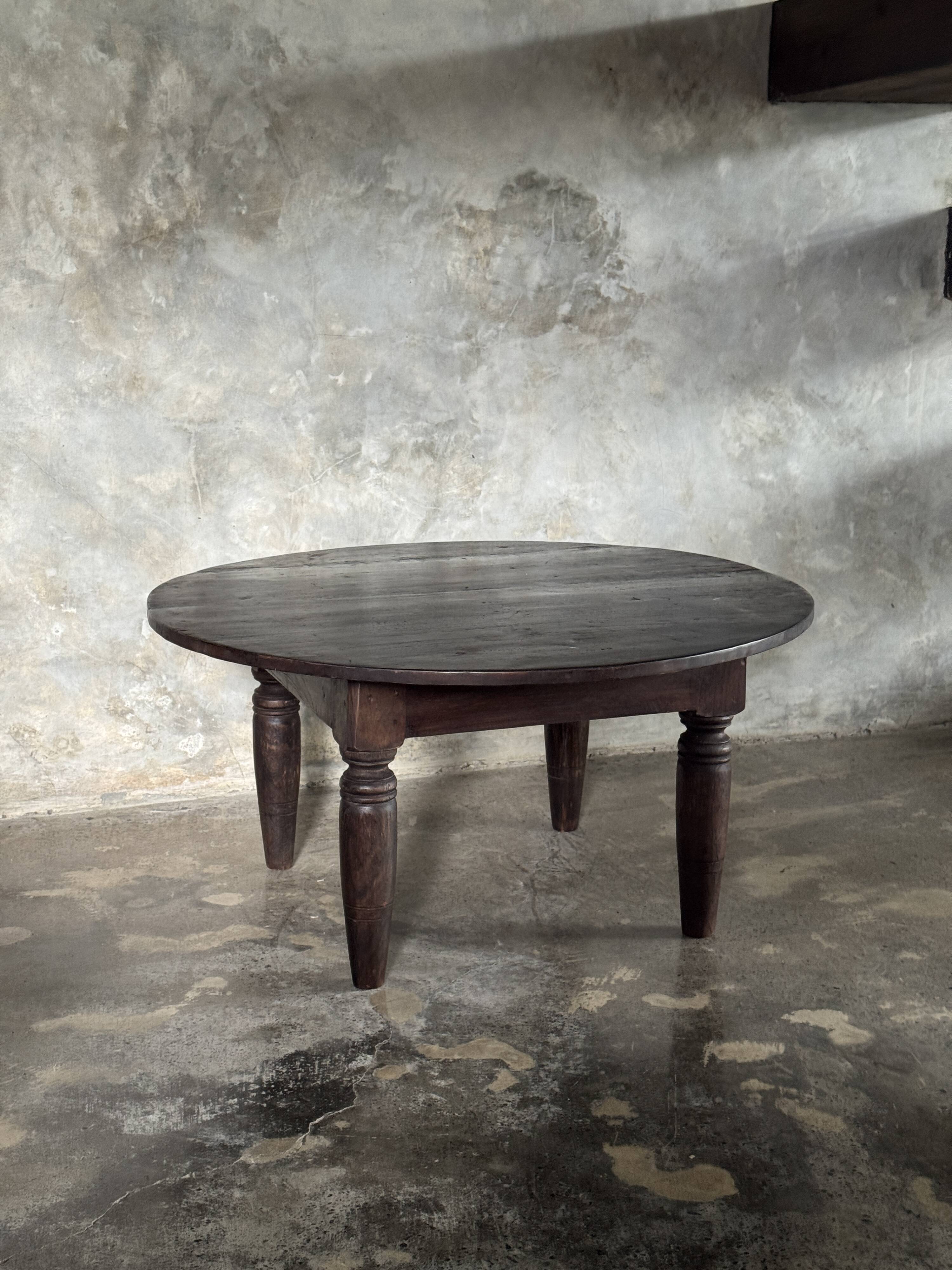 Antique round coffee table in Indonesian teak with turned legs.