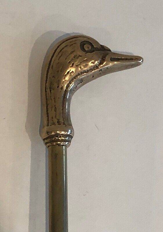 Neoclassical brass fire accessory with duck head decorations.