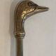 Neoclassical brass fire accessory with duck head decorations.