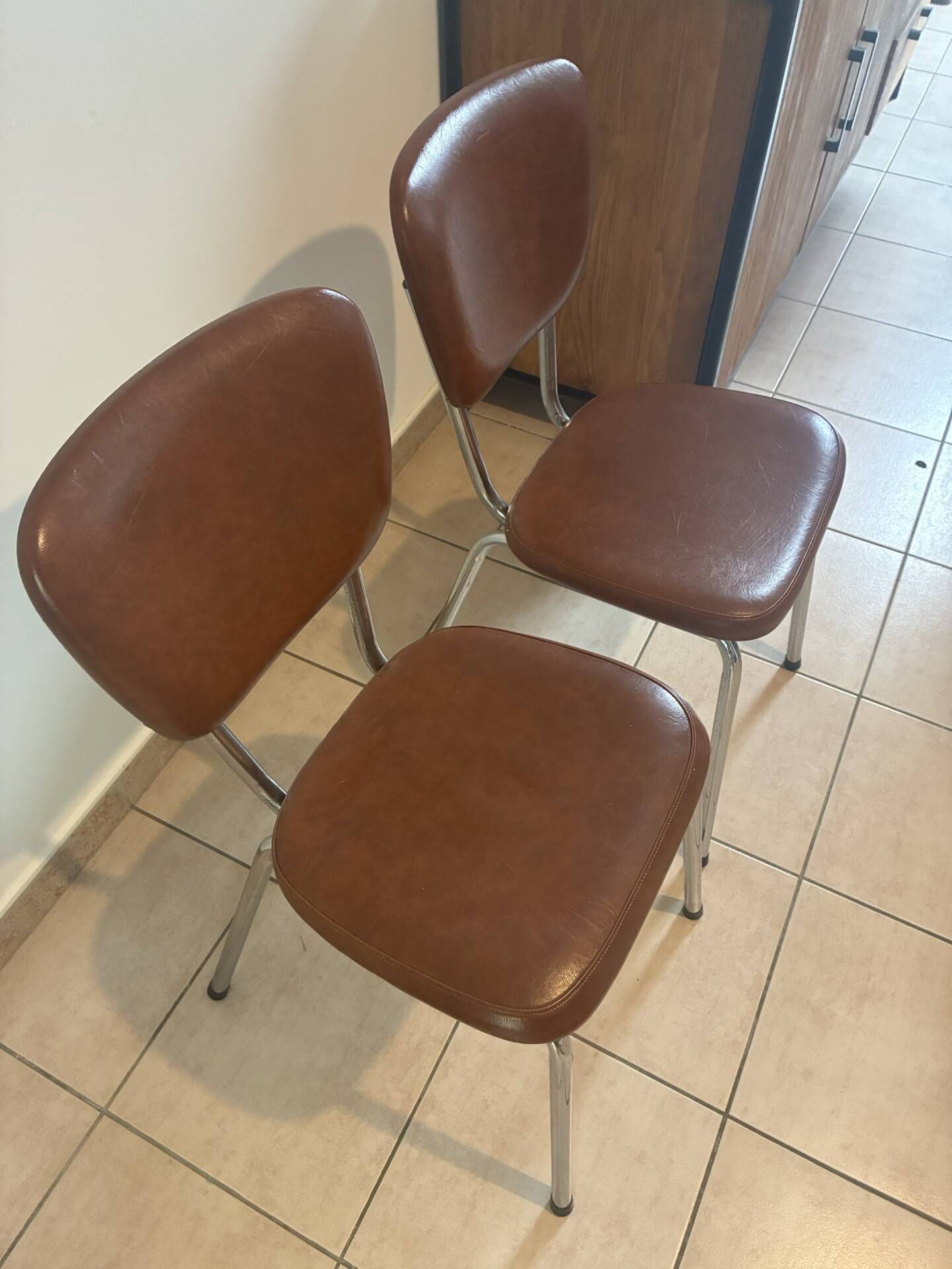 Two brown faux leather chairs.
