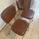 Two brown faux leather chairs.